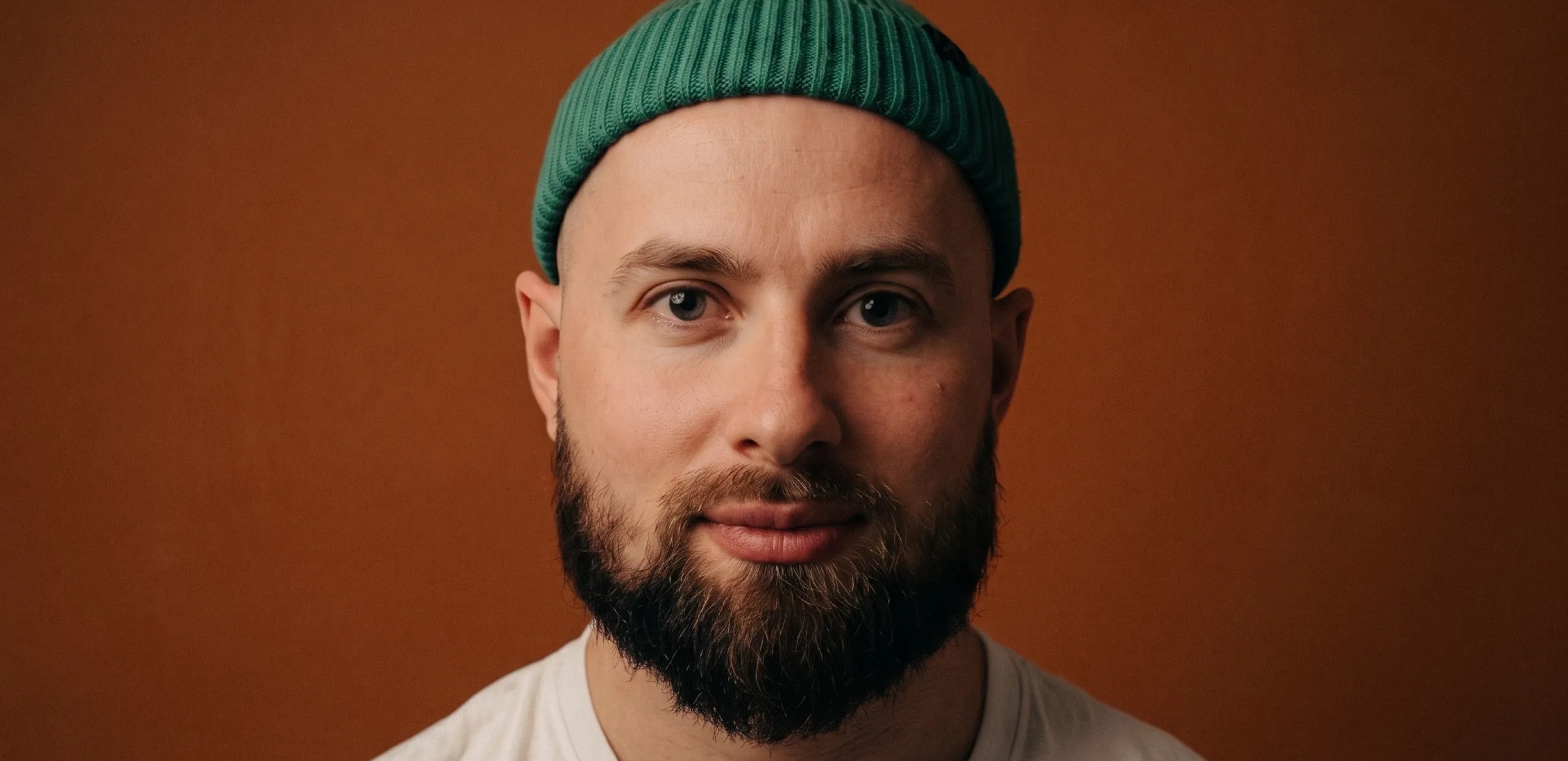 Max Shturma in a green beanie against a rust-coloured backdrop