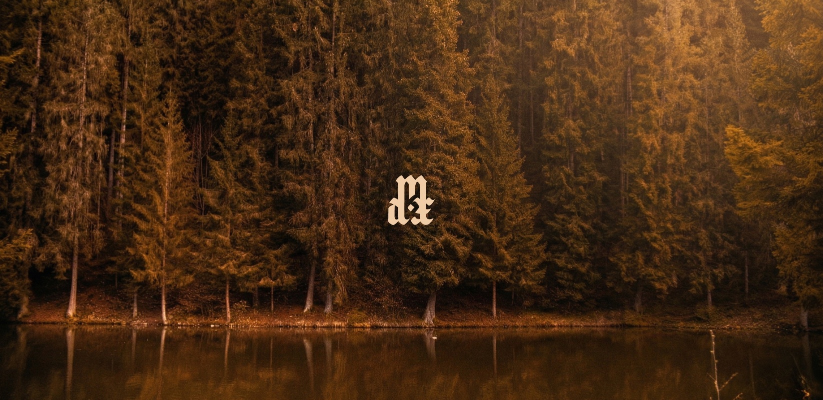 The Mdt monogram in blackletter type, centered over a photo of pine forest reflected in a still lake